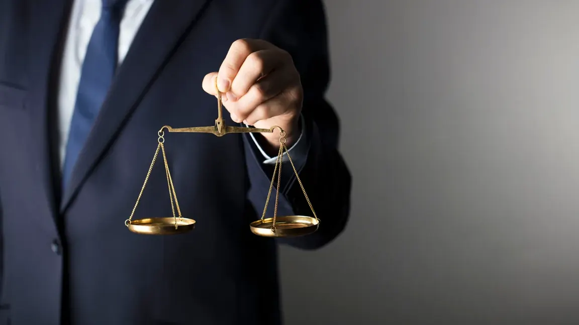 Homem de terno segurando uma balança da justiça